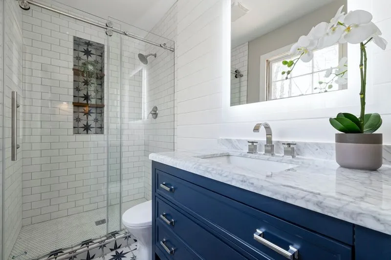 banheiro pequeno decorado na cor branca com armários em azul petróleo